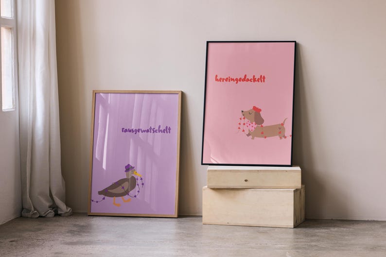 K&ouml;nnte beinhalten: Zwei gerahmte Kunstdrucke. Einer zeigt eine Ente mit lila Hut und dem Text "rausgewatschelt". Der andere Druck zeigt einen Dackel mit rotem Hut und dem Text "hereingedackelt". Beide Drucke sind im Cartoon-Stil gehalten.