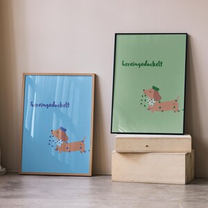 K&ouml;nnte beinhalten: Zwei gerahmte Kunstdrucke mit einer Cartoon-Dackel-Illustration. Einer hat einen blauen Hintergrund, der andere einen gr&uuml;nen Hintergrund. Beide zeigen den Text "hereingedockelt" und einen Dackel mit Hut und Schal.