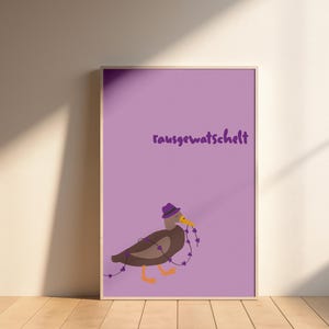 K&ouml;nnte beinhalten: Ein gerahmter Druck mit lila Hintergrund und dem deutschen Text "rausgewatschelt". Der Druck zeigt eine Cartoon-Ente mit lila Hut, die eine Kette aus lila Herzen h&auml;lt. Die Ente hat braune Federn und orangefarbene F&uuml;&szlig;e.