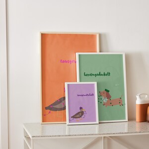 K&ouml;nnte beinhalten: Drei gerahmte Kunstdrucke mit Illustrationen und Text. Der gr&ouml;&szlig;te ist orange mit einem Vogel und rosa Text. Der mittlere Druck ist gr&uuml;n mit einem Dackel und gr&uuml;nem Text. Der kleinste ist lila mit einem Vogel und Text.