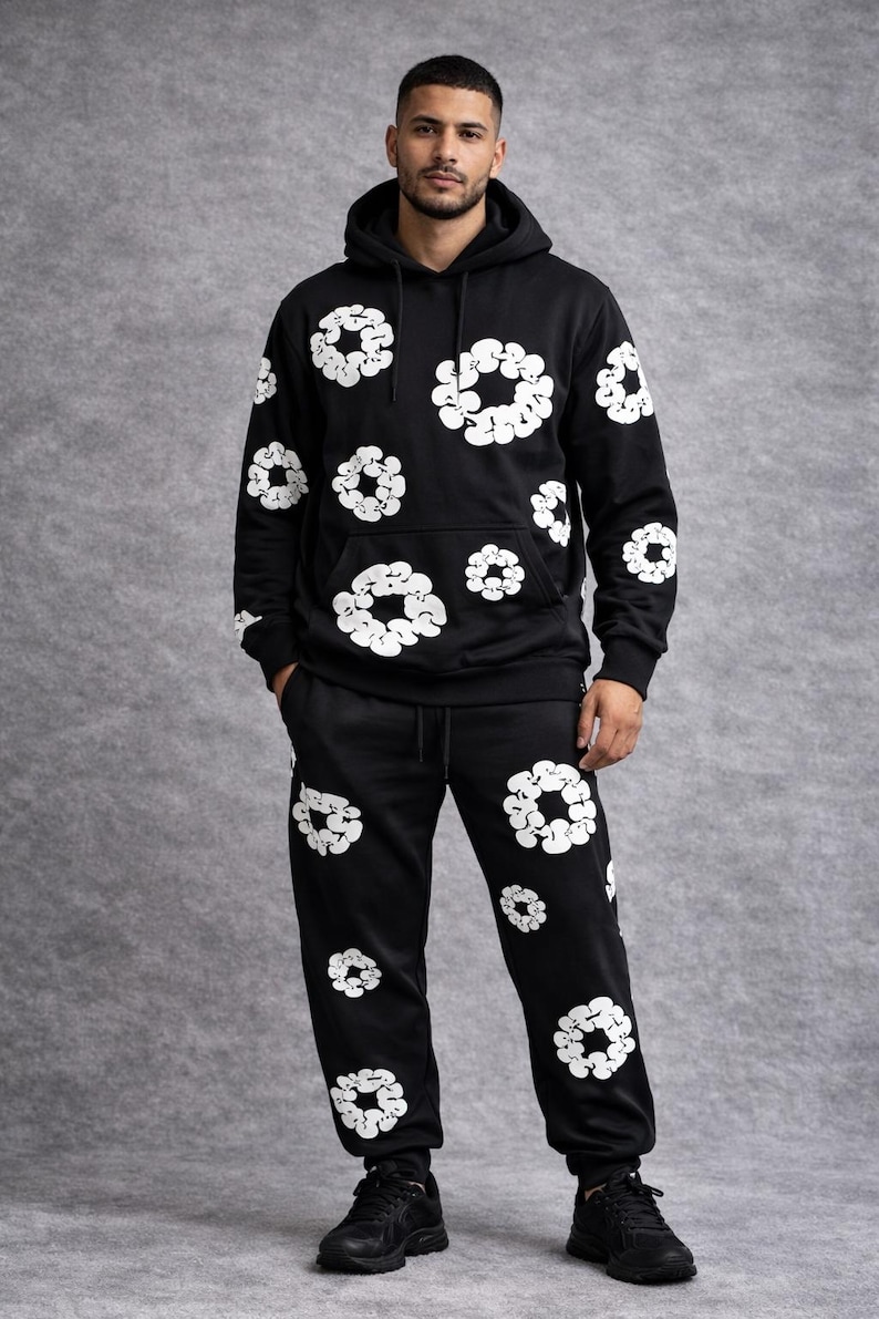 May include: Black hoodie and sweatpants set with a white floral pattern. The hoodie has a drawstring hood and a front pocket. The sweatpants have an elastic waistband and cuffs. The set is made of a soft material and is suitable for casual wear.