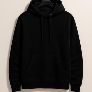 K&ouml;nnte beinhalten: Ein schwarzer Kapuzenpullover mit einer Vordertasche und einer Kapuze mit Kordelzug h&auml;ngt an einem schwarzen Kleiderb&uuml;gel. Der Text "SUPER ARMOUR" ist in gro&szlig;en, fetten, schwarzen Buchstaben &uuml;ber dem Kapuzenpullover aufgedruckt.