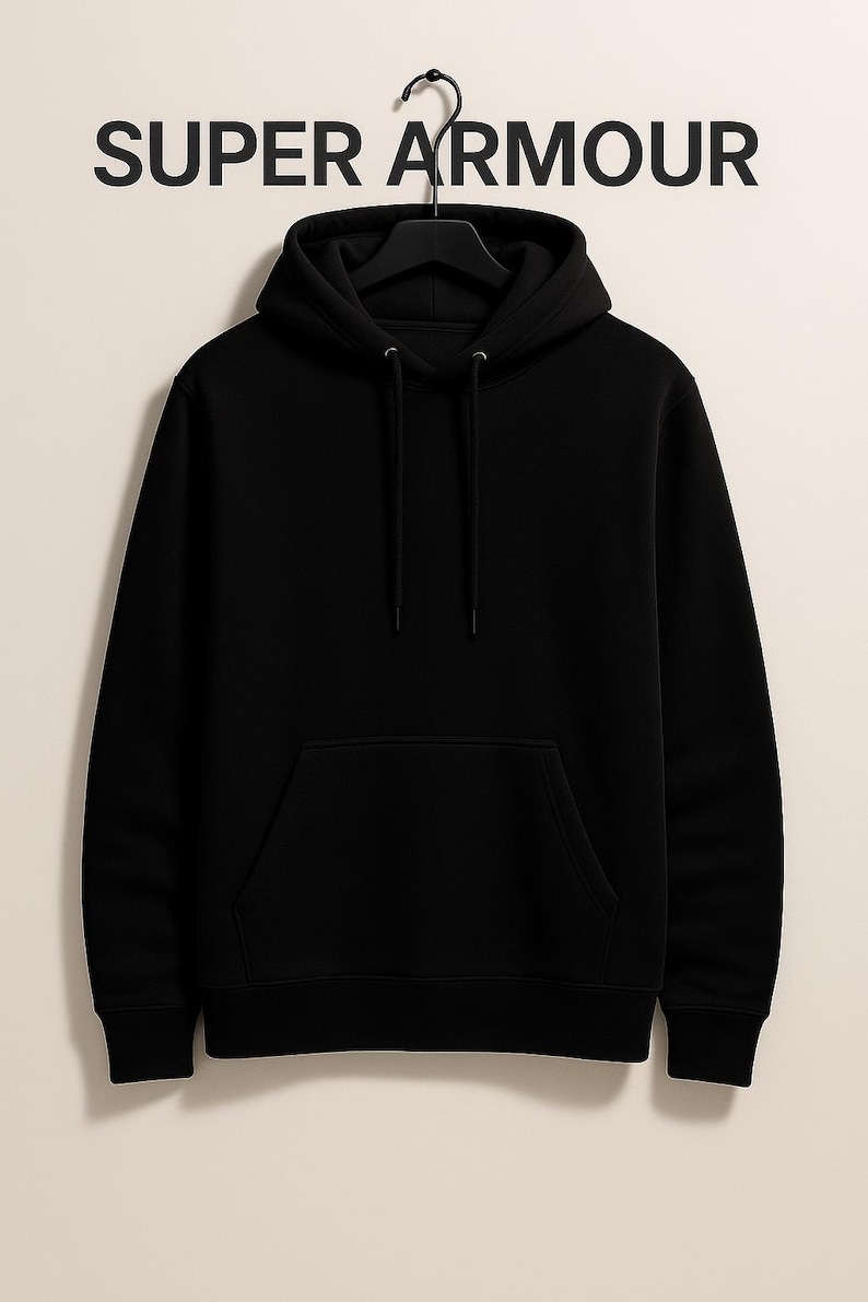 K&ouml;nnte beinhalten: Ein schwarzer Kapuzenpullover mit einer Vordertasche und einer Kapuze mit Kordelzug h&auml;ngt an einem schwarzen Kleiderb&uuml;gel. Der Text "SUPER ARMOUR" ist in gro&szlig;en, fetten, schwarzen Buchstaben &uuml;ber dem Kapuzenpullover aufgedruckt.