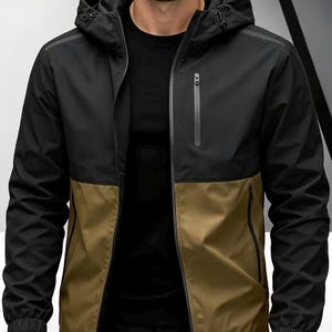 Könnte beinhalten: Eine schwarze und olivgrüne Kapuzenjacke mit Reißverschluss. Die Jacke hat ein zweifarbiges Design, mit Schwarz im oberen Bereich und Olivgrün im unteren Bereich. Sie hat eine Kapuze und zwei Seitentaschen.