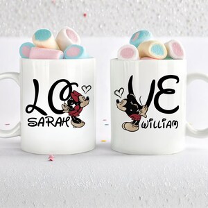 Pu&ograve; includere: Due tazze in ceramica bianca con scritta nera "LOVE" e illustrazioni di Topolino. Una tazza dice "SARAH" e l'altra "WILLIAM". Ogni tazza &egrave; piena di marshmallow colorati.