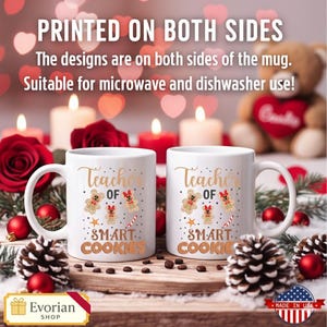 Pu&ograve; includere: Due tazze in ceramica bianca con la scritta "Teacher of Smart Cookies" in lettere dorate, con disegni di biscotti di pan di zenzero. Le tazze sono esposte con decorazioni festive, tra cui candele, rose e pigne. L'immagine include anche la scritta "Printed on Both Sides".