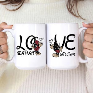 Pu&ograve; includere: Due tazze in ceramica bianca con scritta nera "LOVE" e personaggi dei cartoni animati. Una tazza presenta Minnie Mouse e il nome "Sarah", l'altra presenta Topolino e il nome "William". Ogni tazza ha un simbolo a forma di cuore.