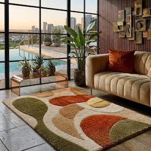 Może przedstawiać: Beżowy dywan z abstrakcyjnym wzorem z zielonych, pomarańczowych i beżowych kształtów. Dywan znajduje się w salonie z beżową sofą, roślinami i widokiem na basen i panoramę miasta przez duże okno.