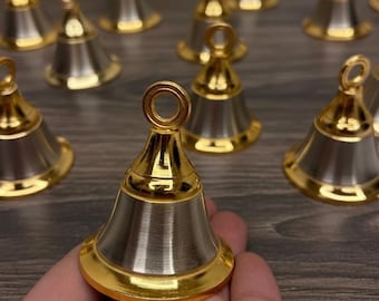 May include: A selection of small, decorative bells. Each bell features a gold-coloured top and base, with a silver-coloured body. The bells are displayed on a wooden surface.