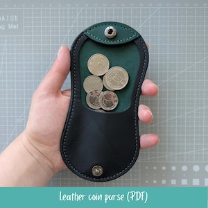 Könnte beinhalten: Schwarzes Leder-Münzportemonnaie mit grünem Innenraum, das mehrere Münzen enthält. Das Portemonnaie hat einen Druckknopfverschluss und ist geöffnet, wodurch die Münzen sichtbar werden. Der Text "Leather coin purse (PDF)" befindet sich unten.