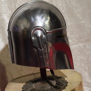 Może przedstawiać: Biały ceramiczny kubek z czarnym uchwytem i napisem "But First, Coffee" pogrubioną, czarną czcionką. Kubek jest ustawiony na rozmytym tle, sugerującym przytulne otoczenie.