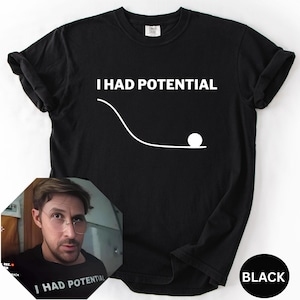May include: Black t-shirt with the text "I HAD POTENTIAL" above a white graphic of a ball rolling down a curved line. A small image of a person wearing the same shirt is in the lower left corner. The word "BLACK" is in a circle in the lower right.