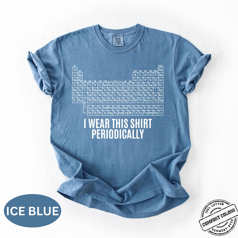 Może przedstawiać: Błękitna koszulka z białym układem okresowym i napisem "I Wear This Shirt Periodically". Koszulka wykonana w 100% z bawełny i barwiona w odzieży.