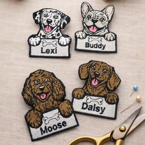 May include: Embroidered dog patches showing a Dalmatian, French Bulldog, Goldendoodle, and Dachshund. Each patch has a name on a sign: Lexi, Buddy, Moose, and Daisy. Sewing tools are visible around the patches.