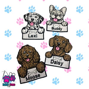 May include: Embroidered patches of four dogs, each holding a sign with a bone and a name: Lexi, Buddy, Moose, and Daisy. The patches are on a white background with pink and blue paw prints.