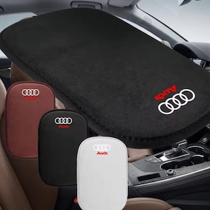 Può includere: Copertura nera del cruscotto dell'auto con il logo Audi in rosso e bianco. L'immagine mostra anche tre coprisedili per auto marroni, neri e bianchi, ciascuno con il logo Audi.
