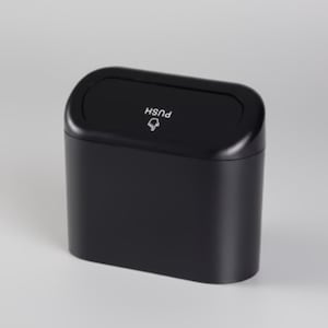 May include: A black, rectangular trash can with a rounded top. The lid has the word "PUSH" and a small graphic. The can is designed with a smooth, matte finish.