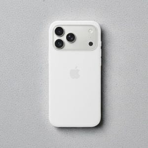 May include: A white smartphone with a triple-lens camera and the Apple logo. The phone is in a white case and is set against a gray speckled background. The camera lenses are black.