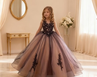May include: A formal dress with a layered skirt. The bodice is black lace, and the skirt is a combination of blush and dark purple tulle. The dress has a V-neck and is suitable for special occasions.