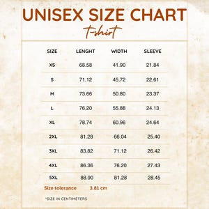 May include: A white unisex t-shirt size chart with brown text. The table lists sizes from XS to 5XL with corresponding length, width, and sleeve measurements in centimeters. The chart includes a size tolerance of 3.81 cm at the bottom.