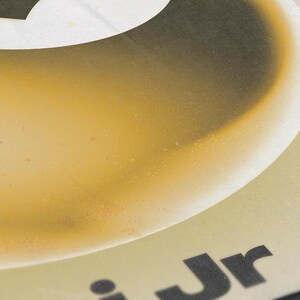 May include: Close-up of a design with a gradient of yellow and brown hues. The top features a white shape with a black outline. The text "Jr" is visible in black at the bottom.