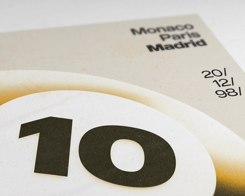 May include: A close-up of a beige and white poster with the number "10" in black on a white circle. The poster also features the words "Monaco Paris Madrid" and the numbers "20/12/981" in black.
