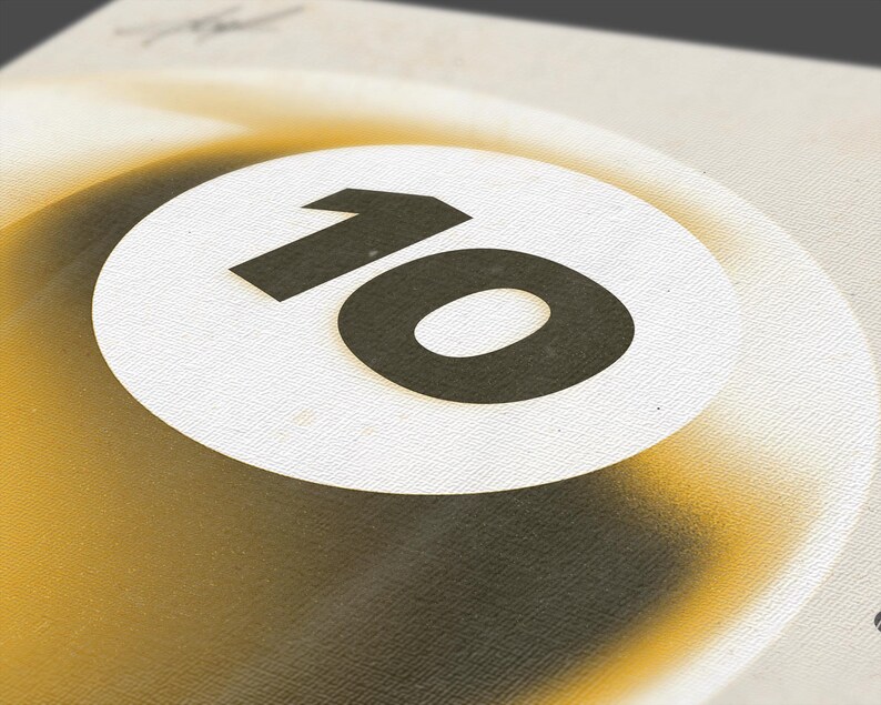 May include: Close-up of a graphic design featuring the number 10 in a bold, black font, centered on a white circle. The circle is set against a gradient background of yellow and black, creating a retro aesthetic. The design has a textured appearance.