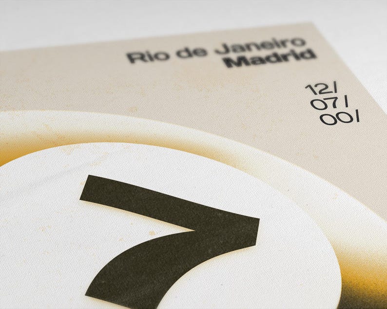 May include: Close-up of a design with the words "Rio de Janeiro Madrid" in black font. A large white circle with a black "7" is in the foreground. The date "12/07/001" is also visible. The background is a light beige color.