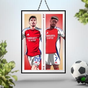 以下が含まれることがあります： 赤と白のユニフォームを着た2人のサッカー選手が描かれた額入りのアートプリント。 Emirates Fly Betterのロゴ入り。 1人は29番、もう1人は7番。 サッカーをテーマにしたアクセサリーで飾られています。