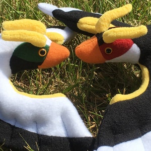 Puede incluir: Dos juguetes de peluche con forma de pájaro con detalles en amarillo, blanco, negro, naranja y rojo. Los pájaros se miran con las alas extendidas.