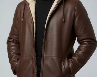 May include: A brown leather coat with a hood and a cream-colored shearling lining. The coat has a zipper closure and pockets. The logo "Rusticdecraft" is visible on the top left. The coat is worn by a person.