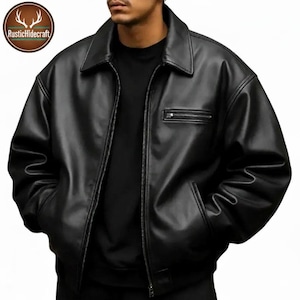 Peut inclure: Veste en cuir noire avec un col, une fermeture éclair sur le devant et deux poches latérales. La veste a une petite poche zippée sur la poitrine et une coupe décontractée. Le logo RusticHidecraft est visible en haut à gauche.