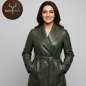 May include: A dark green leather trench coat with a belted waist and large lapels. The coat has long sleeves and pockets. The logo "Rustic Hidecraft" is in a circular wooden frame in the upper left corner.