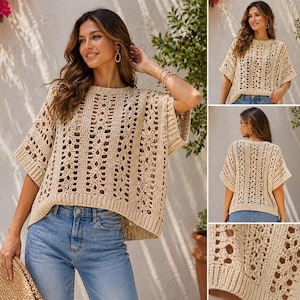 May include: A beige, open-weave crochet top with short sleeves and a round neckline. The top is paired with blue jeans. The crochet design features a repeating pattern of open spaces, creating a textured look. The top is a relaxed fit.