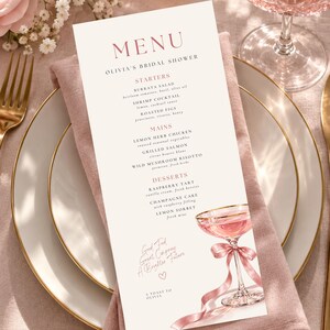 Könnte beinhalten: Eine vertikale, rechteckige Menükarte für Olivias Brautparty, gedruckt auf cremefarbenem Papier mit roségoldenem Text. Das Menü listet Vorspeisen, Hauptgerichte und Desserts auf und zeigt ein Aquarell eines rosa Cocktailglases mit Seidenband.