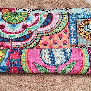 May include: A brightly coloured patchwork clutch bag with a variety of patterns in pink, blue, green, and yellow. The rectangular bag features detailed stitching and a mix of floral and geometric designs, ideal for carrying essentials.