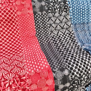 May include: A close-up of patterned fabric in red, black, and blue. The red fabric has polka dots and circular designs. The black and white fabric has geometric shapes, and the blue fabric has polka dots and swirls. Suitable for clothing or home decor.