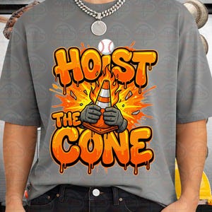 May include: Gray t-shirt with a graphic design featuring the text "HOIST THE CONE" in orange dripping letters. The design includes a baseball, a traffic cone held by gloved hands, and an orange explosion background.