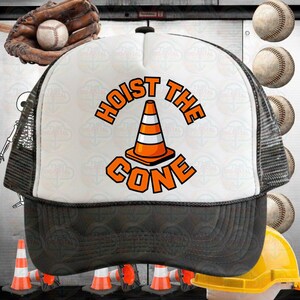 以下が含まれることがあります： 「HOIST THE CONE」の文字とオレンジと白のカラーコーンのグラフィックが特徴の白と黒のトラッカーハット。フロントパネルは白、バックは黒のメッシュ。つばは黒です。