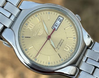 Reloj automático vintage Seiko 5 con esfera dorada con efecto sol y fecha.