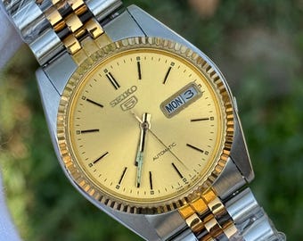 Reloj automático Seiko 5 vintage: esfera dorada, bisel estriado, acero inoxidable.