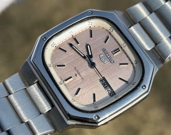Reloj Seiko 5 automático vintage de acero inoxidable: esfera rosa con indicador de día y fecha.