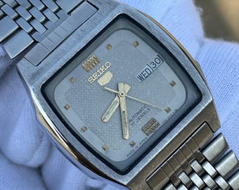 Reloj Seiko 5 vintage automático de 17 joyas, esfera de 36 mm, día y fecha en inglés y árabe, esfera gris texturizada, acero inoxidable.