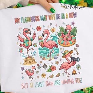 Peut inclure: T-shirt blanc avec une illustration colorée de flamants roses de dessin animé s'amusant. Le texte "MY FLAMINGOS MAY NOT BE IN A ROW BUT AT LEAST THEY ARE HAVING FUN" est imprimé en haut et en bas.