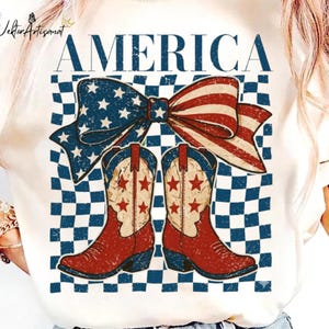 Peut inclure: T-shirt crème avec un motif patriotique. Le motif comprend le mot "AMERICA" au-dessus d'un nœud avec un motif d'étoiles et de rayures, et des bottes de cowboy rouges avec des étoiles. Un motif à carreaux bleu et blanc remplit l'arrière-plan.