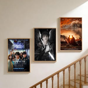 May include: Three framed posters with artwork from "Omniscient Reader" and "My Scient Reader: The Prophecy". The posters are displayed on a white wall near a wooden staircase. The posters feature illustrations and text.