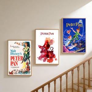May include: Three framed Peter Pan film posters. The posters feature colourful illustrations of Peter Pan, Captain Hook, and other characters. The posters are displayed on a light-coloured wall near a wooden staircase.