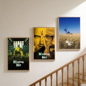 Peut inclure: Trois affiches encadrées représentant des scènes de la série télévisée "Breaking Bad". Les affiches ont des cadres en bois et sont accrochées à un mur beige. Les affiches représentent des personnages et des scènes de la série, avec le titre de l'émission bien en évidence.
