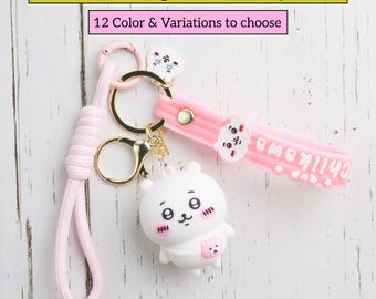 May include: A pink and gold keychain featuring a white cartoon character charm. The keychain includes a pink strap with the text "Chiikawa" and a pink lanyard. The image text reads "Chiikawa Bag Charm Keychain" and "12 Color & Variations to choose".