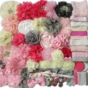 May include: A collection of pink, gray, and white fabric flowers, ribbons, and other embellishments for crafting hair accessories.